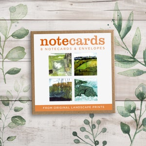 May include: A set of notecards in a brown box, featuring four landscape art prints. The box reads "notecards" and "8 notecards & envelopes". The bottom of the box reads "FROM ORIGINAL LANDSCAPE PRINTS". The background has watercolor leaves.