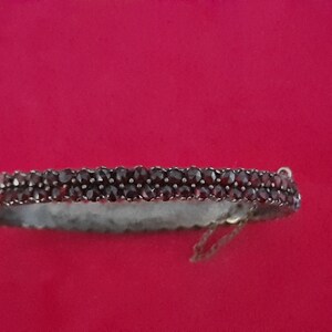 K&ouml;nnte beinhalten: Ein silbernes Armband mit einer doppelten Reihe dunkelroter Granatsteine.