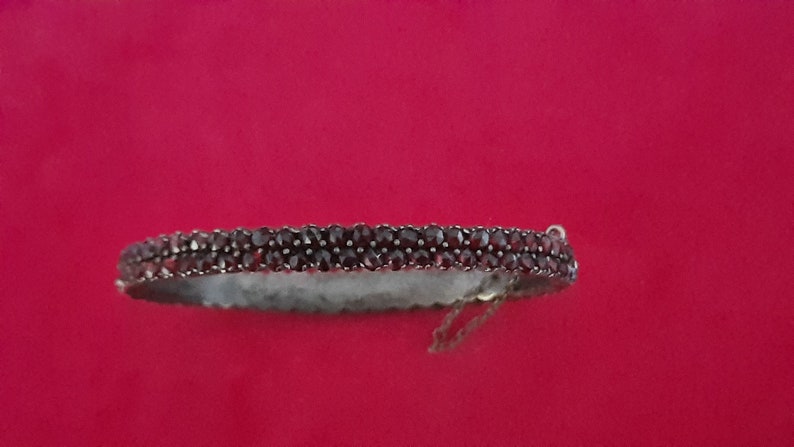 K&ouml;nnte beinhalten: Ein silbernes Armband mit einer doppelten Reihe dunkelroter Granatsteine.