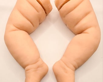 Può includere: Due gambe di bambola realistiche, color pesca chiaro. Le gambe sono poste fianco a fianco, con i piedi rivolti verso il basso. Le gambe sono dettagliate con rughe e pieghe, e la parte superiore delle gambe è tagliata.