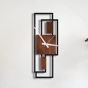 May include: A modern wall clock with a geometric design. The clock features a dark wood face and accents within a black metal frame. The clock hands are white. The text "BLACK. WALDECOR" is in the upper right corner.