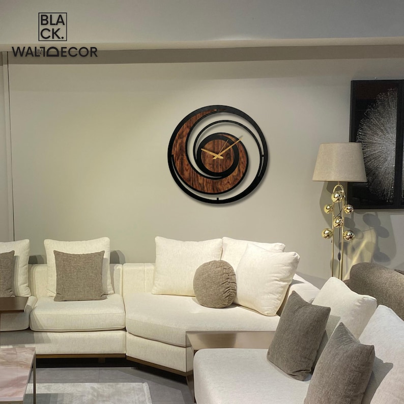 May include: A modern wall clock with a spiral design. The clock features a dark brown wooden center with a black outer frame. Gold-colored hands indicate the time. The text "BLACK. WALDECOR" is visible in the upper left corner.