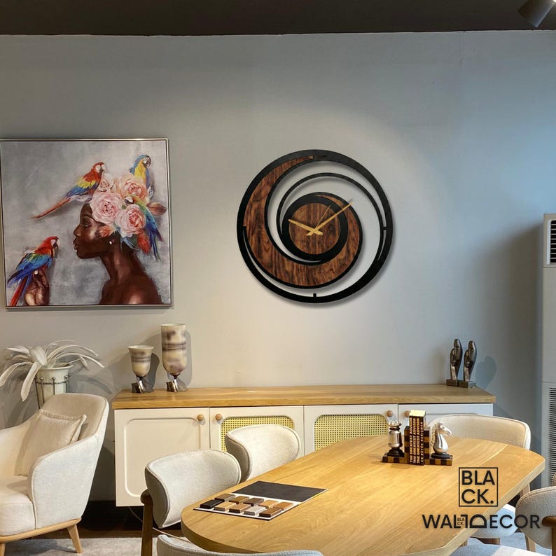 May include: A modern wall clock with a spiral design. The clock features a dark wood grain center, black metal frame, and gold-colored hands. The clock is mounted on a light gray wall, with a painting and furniture in the background.