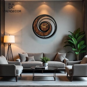 May include: A large, round wall clock with a spiral design. The clock features a dark brown wooden center, a black metal frame, and gold-colored hands. The text "BLACK. WALDECOR" is visible in the upper left corner. The clock is mounted on a gray wall.