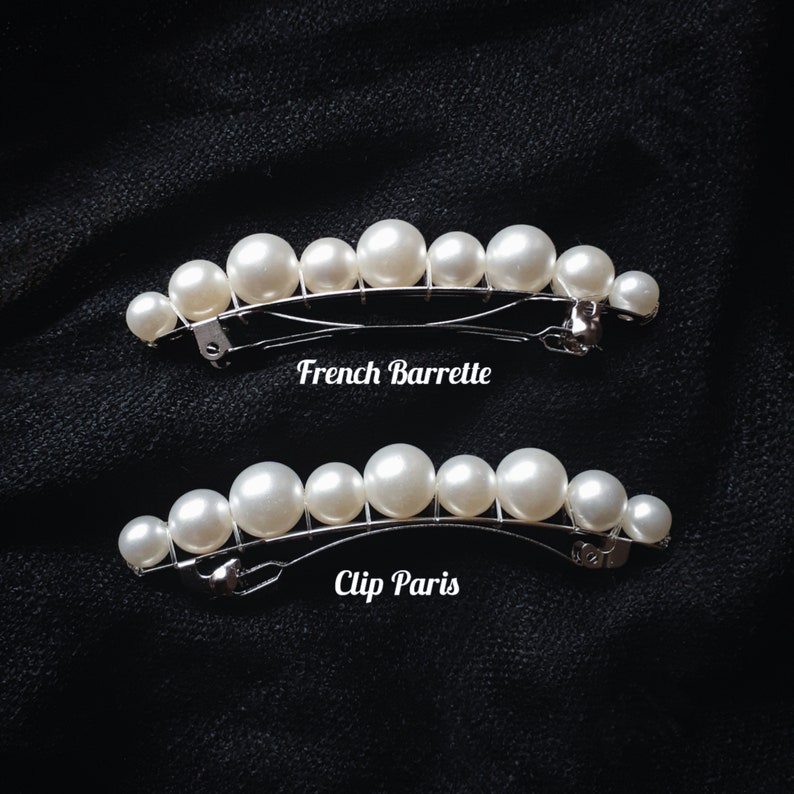 K&ouml;nnte beinhalten: Zwei silberne Haarklammern mit einer Reihe wei&szlig;er Kunstperlen. Die obere Klammer ist mit "French Barrette" und die untere mit "Clip Paris" beschriftet.