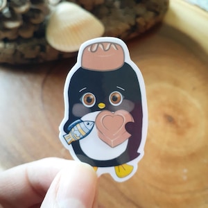 Petit pingouin avec poisson et chocolats ; Autocollant en vinyle. Bonbons et bonbons. Noeud papillon noir et blanc. Art d'oiseau adorable.