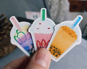 May include: Three colorful bubble tea stickers with different flavors. The stickers feature a pink bubble tea with strawberries, a blue bubble tea with mango, and a yellow bubble tea with tapioca pearls.