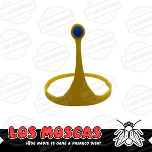 May include: A yellow plastic crown with a blue plastic jewel on top. The crown is shaped like a traditional crown with a pointed top and a circular base. The text "LOS MOSCAS ¡QUE NADIE TE GANE A PASARLO BIEN!" is printed below the crown.