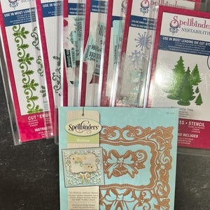 Könnte beinhalten: Ein Set Spellbinders Stanzschablonen zum Basteln. Das Set enthält eine Vielzahl von Designs zum Thema Weihnachten, darunter einen Rahmen mit Schleifen, einen Rand mit Stechpalme und einen Satz Weihnachtsbäume. Die Stanzformen sind aus Metall und kompatibel mit den meisten gängigen Stanzmaschinen.