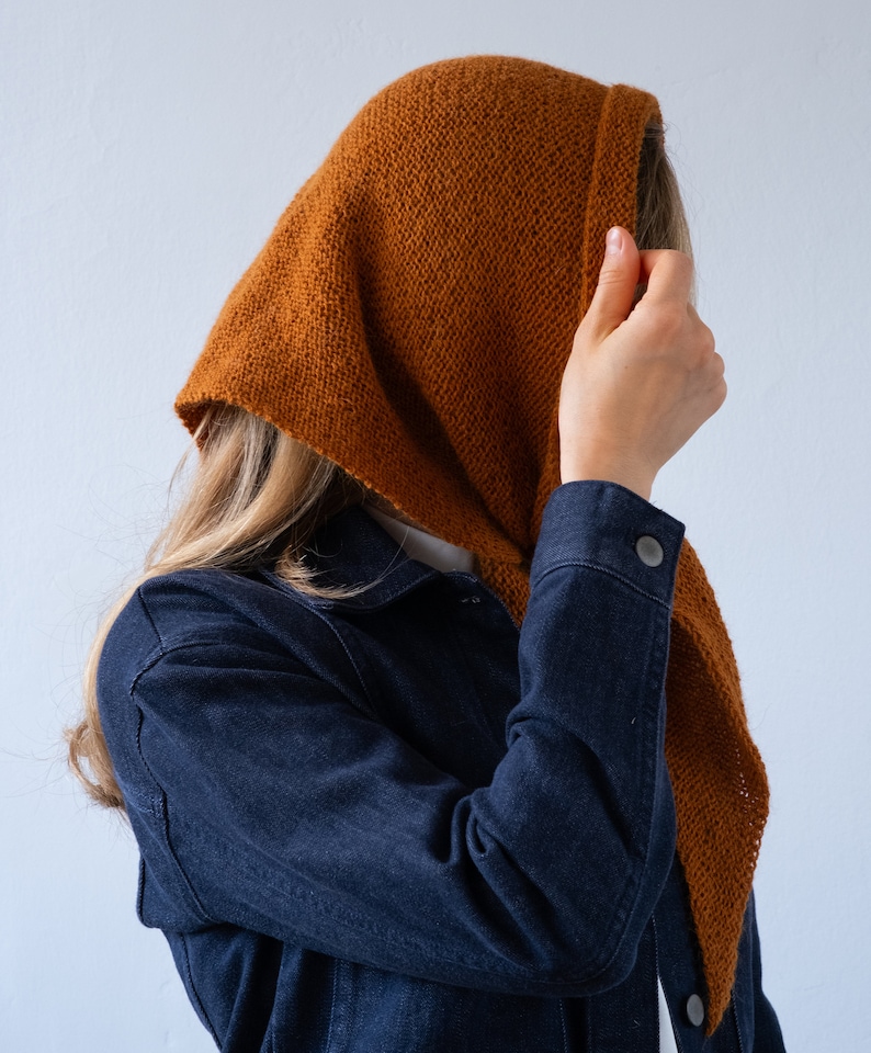 May include: A person wearing a brown hooded scarf over their head and a dark blue denim jacket.