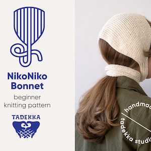 May include: A white knitted bonnet with a long, pointed flap at the back. The bonnet is being worn by a person with long brown hair. The text "handmade goods tadekka studio" is visible in the bottom right corner of the image.