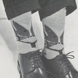 Può includere: Un paio di scarpe nere in pelle con lacci e calzini grigi con un design a forma di volpe. I calzini sono lavorati a maglia con uno sfondo bianco e un viso di volpe marrone.