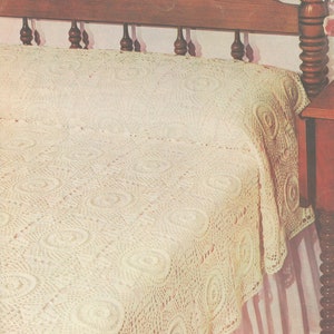May include: A white crocheted bedspread with a delicate floral pattern. The bedspread is on a bed with a wooden headboard and a white bed skirt.