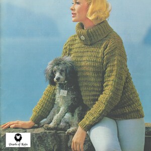 May include: A woman wearing a green turtleneck sweater with a small button on the collar, sitting on a rock with a small gray poodle dog. The woman is wearing white pants and has blonde hair. The background is a blue sky and water.