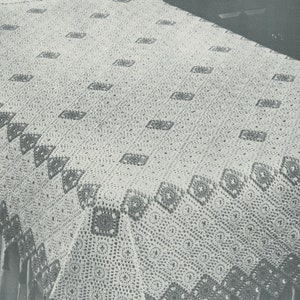 May include: A white crocheted bedspread with a diamond pattern and fringe. The bedspread is on a bed with a white pillow.