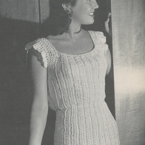May include: A white crochet top with a scoop neck and short sleeves. The top has a fitted bodice and a slightly flared skirt.