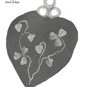May include: A grey crocheted heart-shaped hot pad with a white crocheted design of leaves and flowers. The hot pad has a loop at the top for hanging.