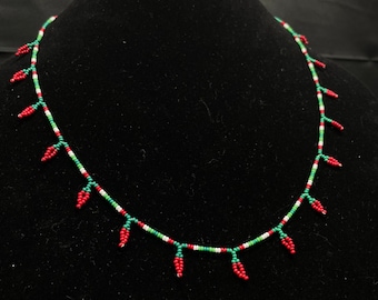 May include: A red, green, and white beaded necklace with red chili pepper charms.