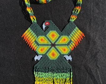 May include: A beaded necklace with a green, yellow, and orange eagle design. The necklace has a fringe of beads at the bottom.