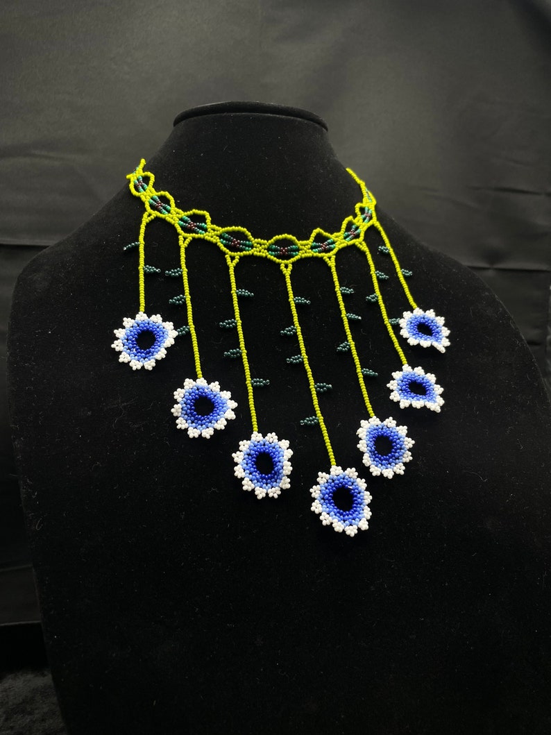 May include: A beaded necklace with a green and white base and blue and white flower accents.