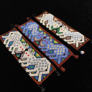 May include: Three beaded bracelets with colorful geometric patterns. The bracelets are made with small, colorful beads and feature a white, blue, and brown color scheme.