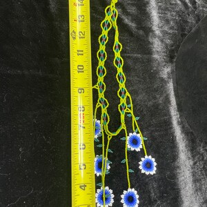 May include: A beaded necklace with a green and blue floral design. The necklace is approximately 15 inches long and features a series of blue and white flowers.