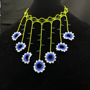 May include: A beaded necklace with a green and black base and blue and white flower accents.