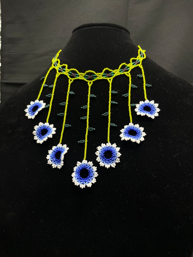 May include: A beaded necklace with a green and black base and blue and white flower accents.