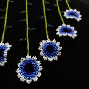 May include: A beaded necklace with a green and white base and blue and white flower accents.