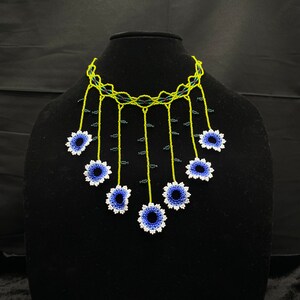 May include: A beaded necklace with a green and black choker and blue and white flower accents.