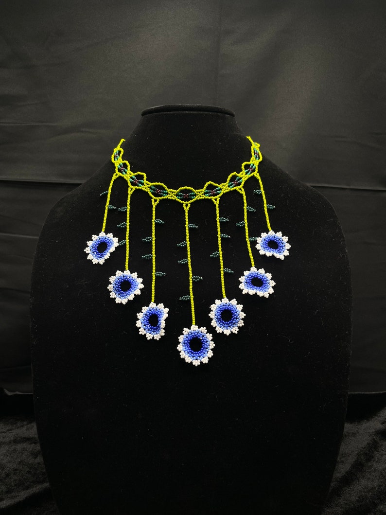 May include: A beaded necklace with a green and black choker and blue and white flower accents.