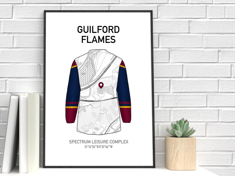 May include: A framed print featuring a stylized illustration of a Guilford Flames jersey. The jersey design incorporates a map-like pattern with navy blue sleeves, accented with red and gold stripes. Text at the top reads "GUILFORD FLAMES".