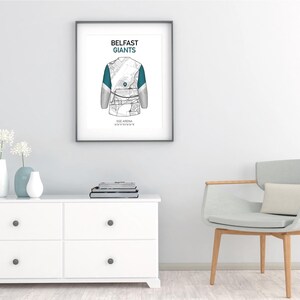 May include: Framed art print featuring a detailed illustration of a hockey jersey, with the text "Belfast Giants" at the top. The jersey design incorporates teal accents. Below the jersey is the text "SSE Arena, Belfast".