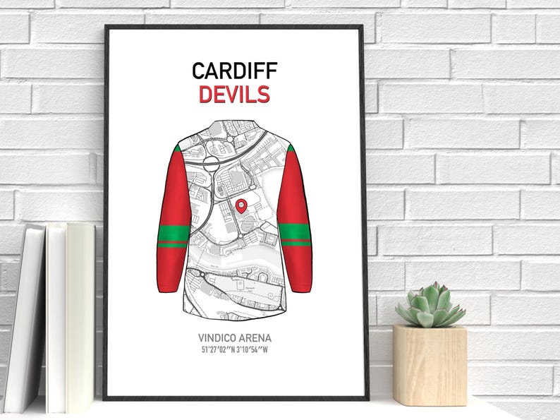 May include: A framed print featuring a stylized jersey design with a map overlay. The jersey has red sleeves with green stripes and a white body. The text "CARDIFF DEVILS" is at the top, and "VINDICO ARENA" with coordinates is at the bottom.