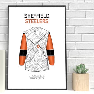 May include: A framed print featuring a stylized map design of a hockey jersey. The jersey is white with orange sleeves and black accents. The text "SHEFFIELD STEELERS" is at the top, with "UTILITA ARENA" and coordinates at the bottom.