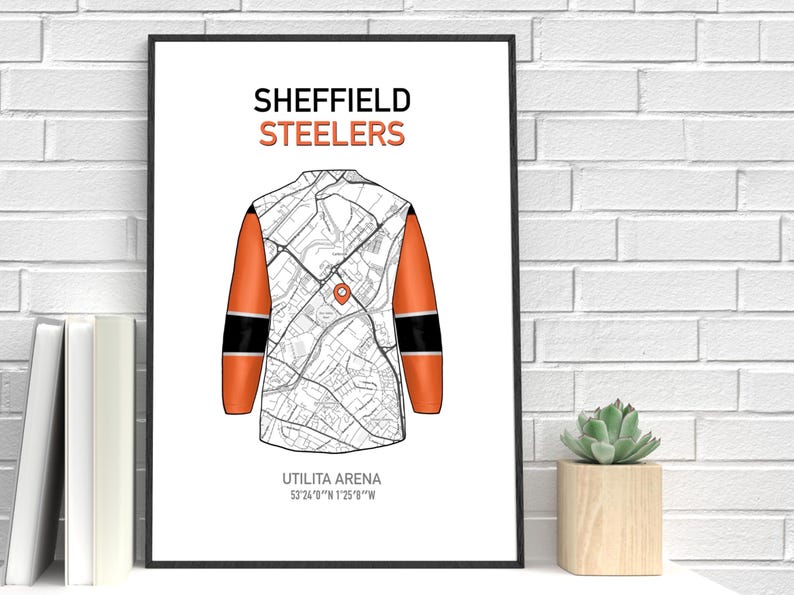May include: A framed print featuring a stylized map design of a hockey jersey. The jersey is white with orange sleeves and black accents. The text "SHEFFIELD STEELERS" is at the top, with "UTILITA ARENA" and coordinates at the bottom.