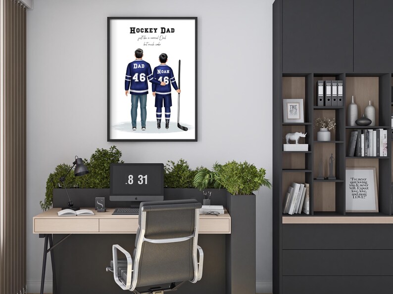 Pu&ograve; includere: Stampa incorniciata con padre e figlio in maglie da hockey, con la scritta "Hockey Dad". Le maglie blu hanno dettagli bianchi e il numero 46. L'immagine &egrave; esposta sopra una scrivania con un computer e una sedia da ufficio nera.