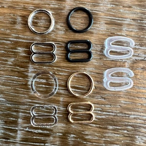 May include: Assortment of bra strap adjusters in different colors and materials.  There are silver, black, clear plastic, and gold adjusters.  Some are round, some are oval, and some are double-loop.