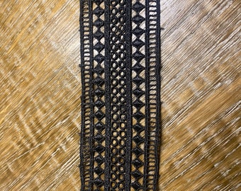 May include: Black lace trim with a repeating pattern of circles and diamonds.