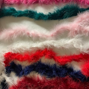 Op de afbeelding: Assortiment van kleurrijke verenboa's in roze, teal, lichtroze, wit, rood, donkerblauw en bordeaux.