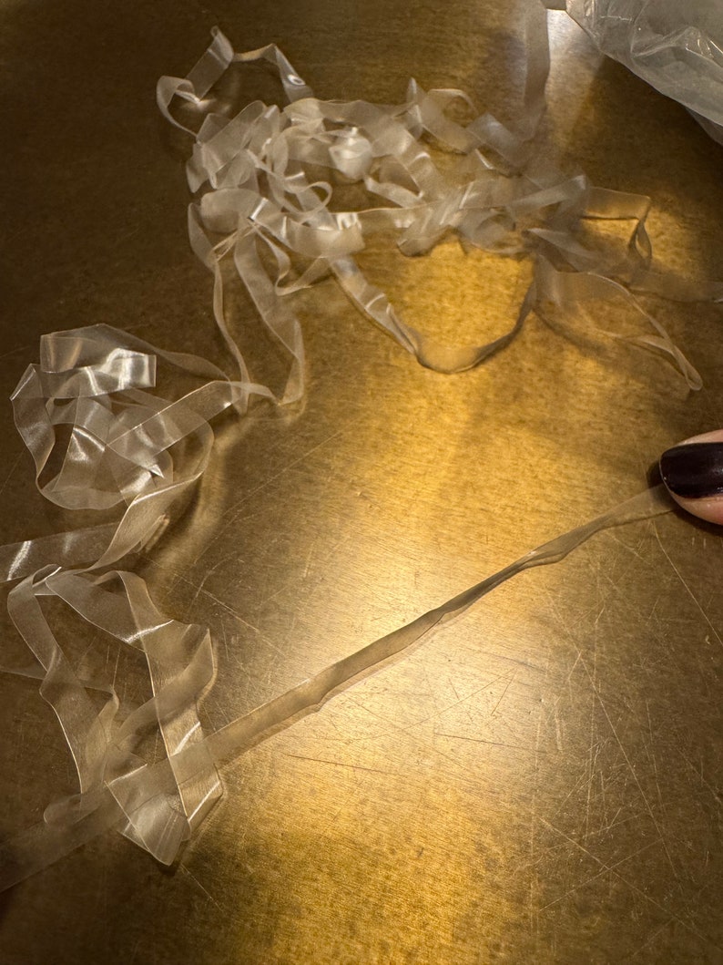 May include: A pile of clear elastic bands on a gold surface.