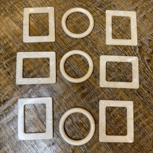 以下が含まれることがあります： 木製の表面に、大理石模様の白いプラスチック製の形が9つ並んでいます。そのうち3つは正方形、3つは円形です。