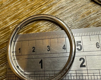 May include: A silver metal ring measuring 5 cm in diameter, placed on a ruler for size reference.