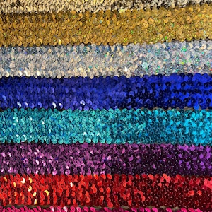 May include: A close-up of seven rows of sequined trim in various colours, including gold, silver, blue, teal, purple, red, and pink.