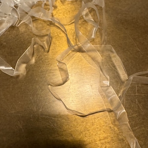 May include: A pile of clear, translucent ribbon on a brown wooden surface.