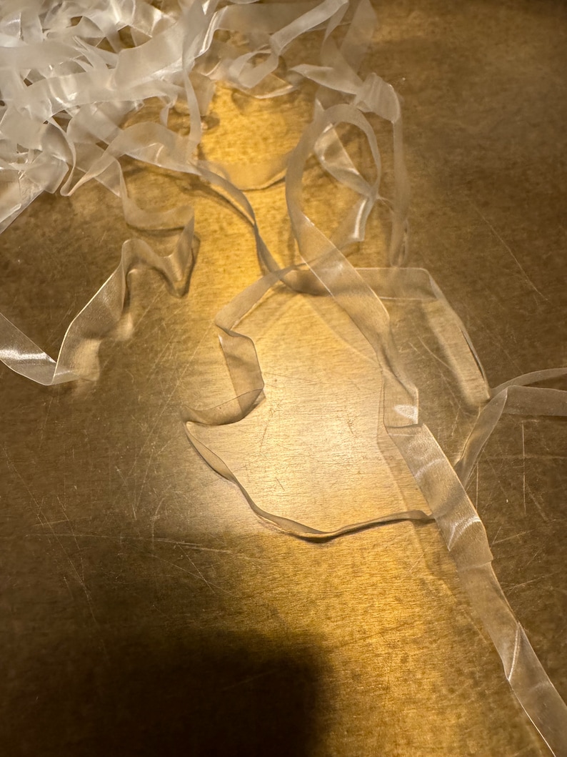 May include: A pile of clear, translucent ribbon on a brown wooden surface.