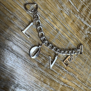 May include: A silver chain bracelet with a charm that spells out the word "LOVE".