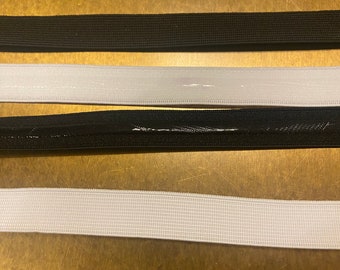 May include: Close-up of four elastic bands in black and white. The bands are arranged horizontally, with two black and two white bands. The bands have a textured surface and are likely used for clothing or crafts.