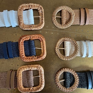 Op de afbeelding: Zes geweven riemen van wilgentenen met verschillende gekleurde stoffen banden en gespen. De riemen zijn gerangschikt in twee rijen van drie. De riemen zijn allemaal gemaakt van natuurlijke materialen en hebben een rustieke uitstraling.