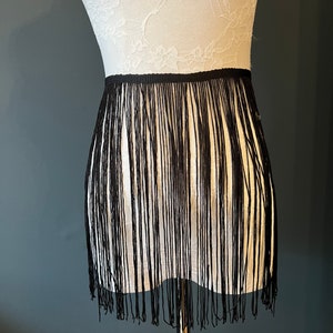 May include: Black fringe trim with a straight edge. The fringe is approximately 2 inches long.